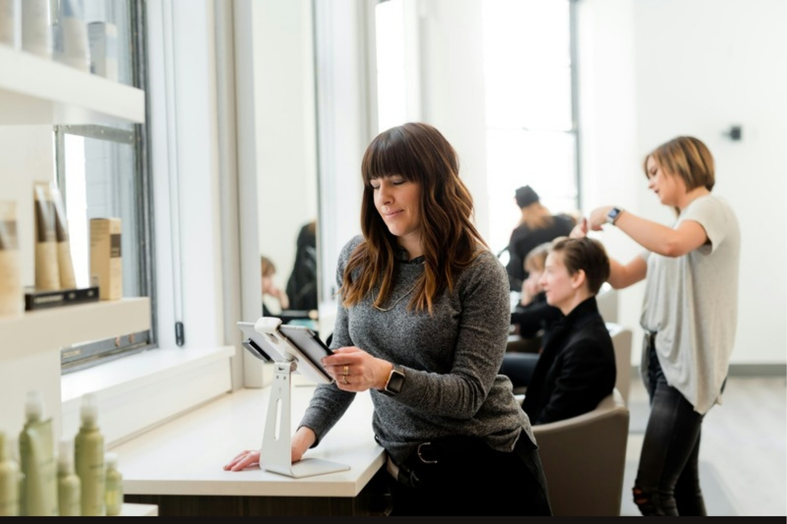 Beauty professional checking her online booking calendar on a tablet at her station